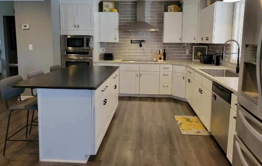 Kitchen after remodel: white shaker cabinets, tile backsplash, new island